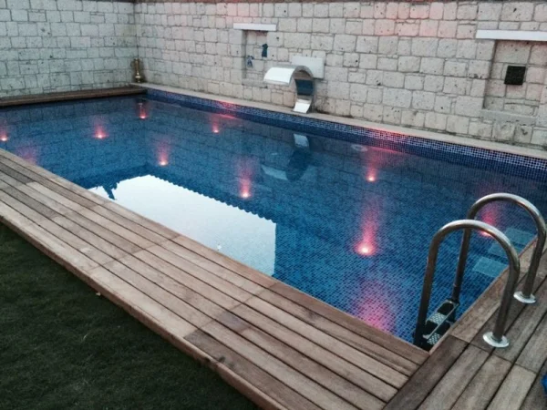 Mavi Derinlik ve Sıcak Ahşap: Çeşme Gizli Savaklı Havuz ve Tabandan Aydınlatma Konsepti
