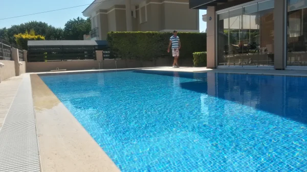 Çeşme'de Klasik Uyum: Traverten Teraslı ve Mavi Mozaikli Üstten Taşmalı Havuz Konsepti Detay
