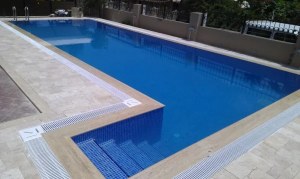Çeşme'de Klasik Uyum: Traverten Teraslı ve Mavi Mozaikli Üstten Taşmalı Havuz Konsepti Detay