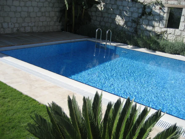 Çeşme'de Doğal Ahenk: Üstten Taşmalı Mavi Cam Mozaik Havuz ve İroko Detayları Detay