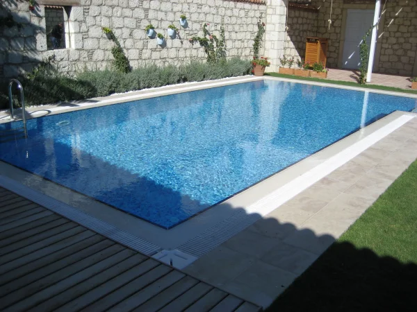 Çeşme'de Doğal Ahenk: Üstten Taşmalı Mavi Cam Mozaik Havuz ve İroko Detayları Detay